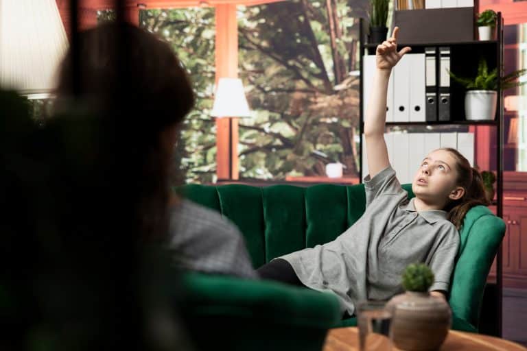 Psychologist listens to girl at counseling session dealing with anxiety