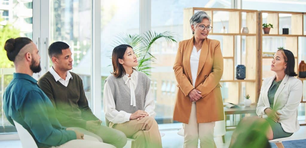 Support, group therapy and senior woman talking in meeting, conversation and wellness. Counseling,